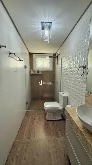 Hall de banheiro com piso de cerâmica e box de vidro.