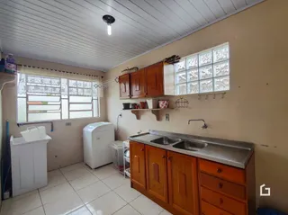 A foto mostra uma cozinha com armários de madeira e piso cerâmico.