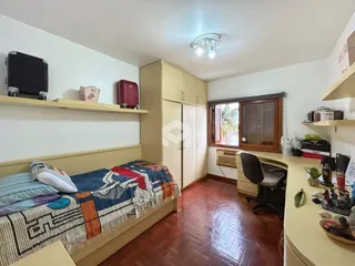 Quarto com cama e armários em madeira em uma residência.