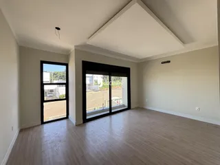Interior de uma sala com piso de madeira e grandes portas de vidro.