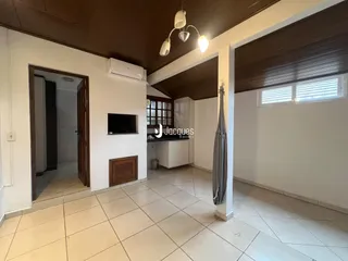 Ambiente interno de sala com piso de cerâmica e teto de madeira.