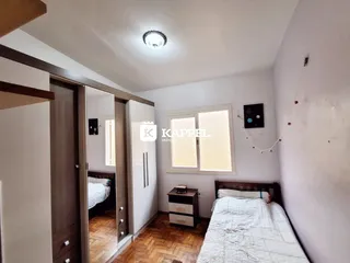 Quarto com cama e armário em um ambiente interno com piso de madeira.