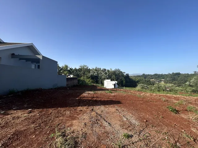 Vista externa de uma propriedade com terreno aberto e construção branca.