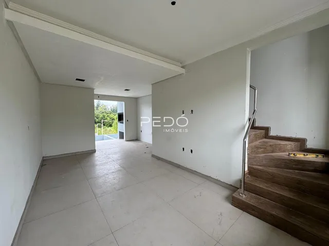 Hall de entrada com piso de cerâmica e escadaria de madeira em imóvel no Lajeado.