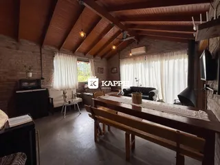 Sala de estar com pé direito alto e vigas de madeira expostas.