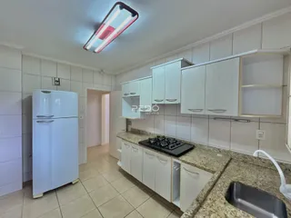 Foto de uma cozinha com armários brancos e bancada de granito.