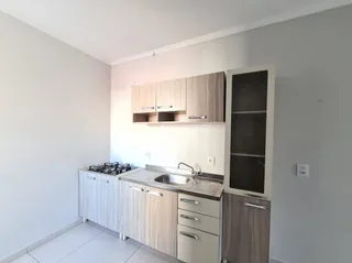 Vista interna de uma cozinha com armários de madeira e bancada clara.