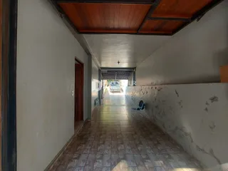 Corredor interno de um imóvel com piso de cerâmica e paredes brancas.