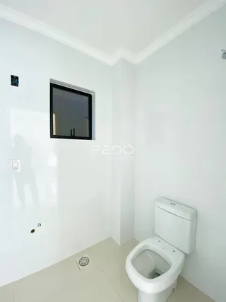 Foto interna de um ambiente com paredes brancas e um vaso sanitário.