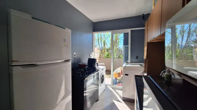 Foto de uma cozinha com armários brancos e eletrodomésticos.