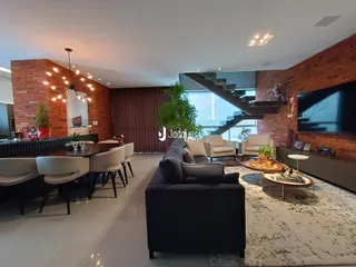 Sala de estar e jantar com paredes de tijolo aparente e escadaria moderna.
