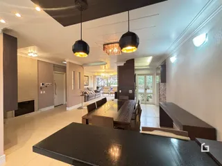 Sala de estar com mesa de jantar de madeira e iluminação moderna.