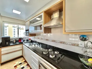 Cozinha moderna com armários e bancadas escuras em um apartamento no Brasil.