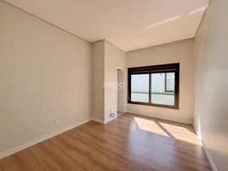 Imagem de uma sala de estar com piso de madeira clara e grande janela.