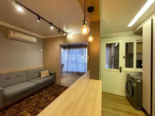 Sala de estar com sofá e piso de madeira em um imóvel no Brasil.