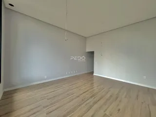 Ambiente interno de uma sala com piso de madeira clara e paredes brancas.