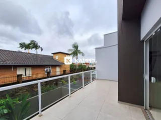A foto mostra uma varanda externa com piso de concreto e grade branca.
