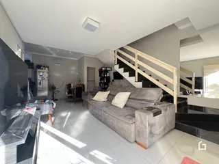 Sala de estar moderna com sofá grande e escadaria em um apartamento.