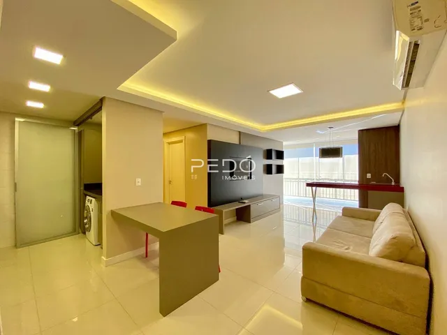 Sala de estar moderna com decoração clara e piso de porcelanato.