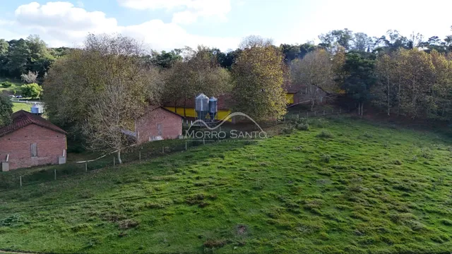 Vista externa de uma propriedade com campo gramado e estruturas rústicas.