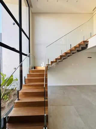 Vista de uma escadaria moderna com guarda-corpos de vidro em um imóvel.