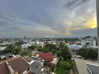 Vista panorâmica de telhados residenciais em Lajeado, Brasil, ao pôr do sol.