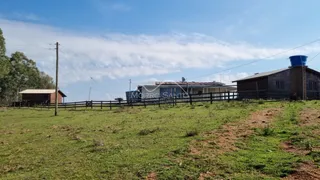 Vista externa de uma propriedade rural com campo gramado e cerca de madeira.