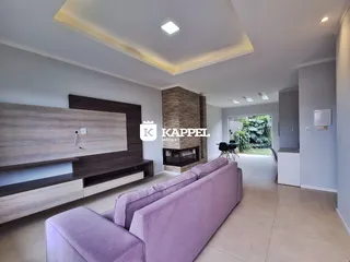 A sala de estar apresenta um sofá grande e uma lareira em um ambiente claro.