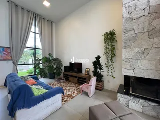 Sala de estar com grandes janelas e lareira de pedra.