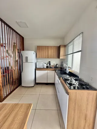 Vista interna de uma cozinha com armários de madeira e piso de cerâmica.