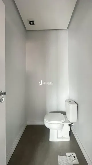 Corredor interno com piso claro e vaso sanitário branco.