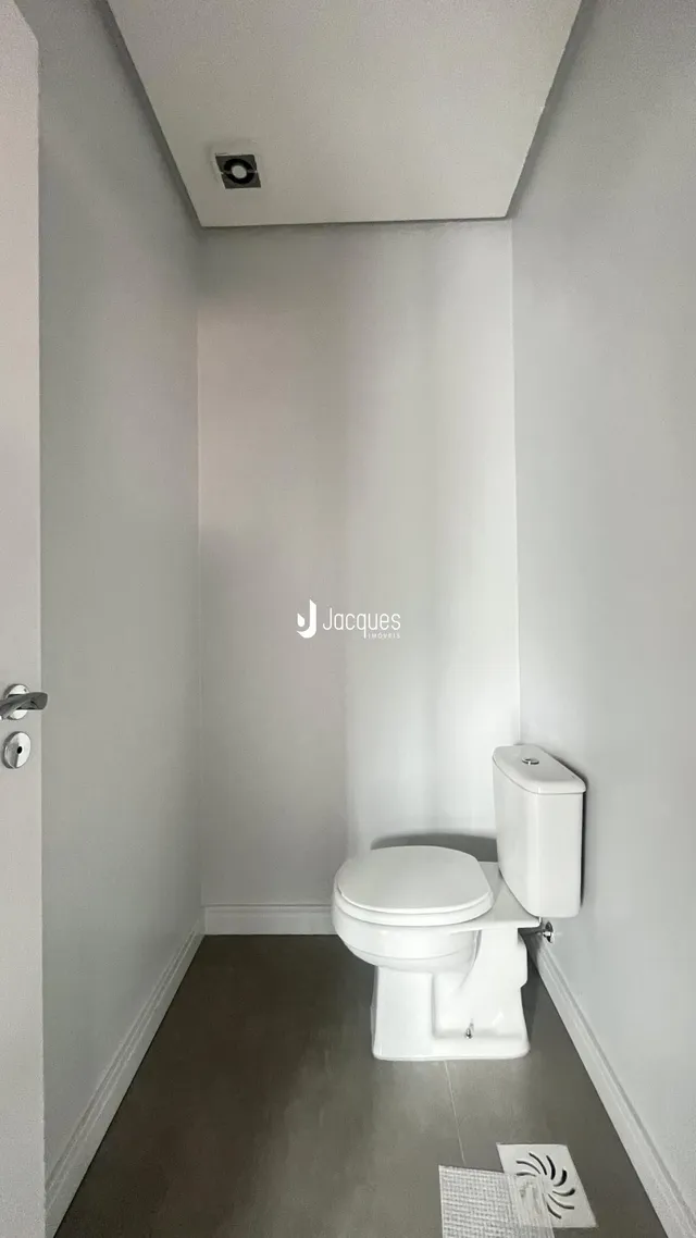 Corredor interno com piso claro e vaso sanitário branco.
