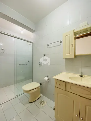 Um banheiro com revestimento cerâmico branco e box de vidro.