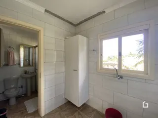 Interior de um corredor com paredes brancas e piso de cerâmica.