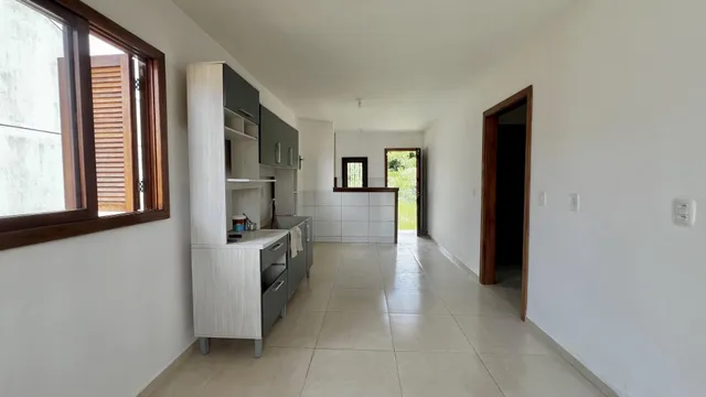 Cozinha moderna com armários e piso de cerâmica em ambiente claro.