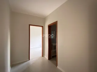 Corredor interno de uma residência com paredes claras e porta de madeira.