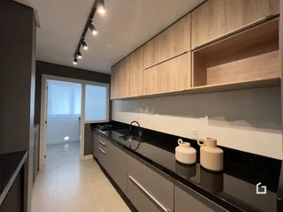 Uma cozinha moderna com armários de madeira e bancadas escuras.