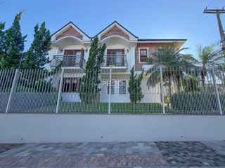 Fachada de uma residência em Lajeado, Brasil, com cerca e vegetação ao redor.