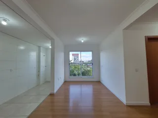 A sala apresenta piso de madeira e paredes brancas em um ambiente interno.
