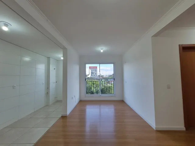 A sala apresenta piso de madeira e paredes brancas em um ambiente interno.