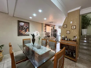 Vista de uma sala de jantar com mesa de vidro e móveis de madeira.