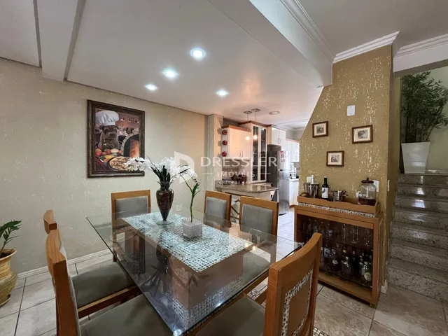 Vista de uma sala de jantar com mesa de vidro e móveis de madeira.