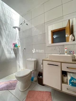Banheiro com revestimento cerâmico e louças brancas.