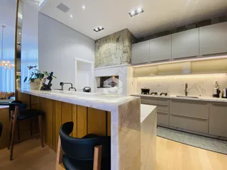A cozinha apresenta armários modernos e bancadas de mármore.