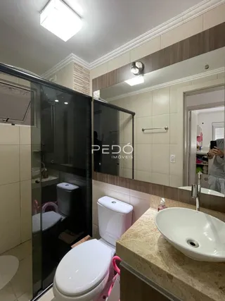 Foto de um banheiro moderno com box de vidro e louças brancas.