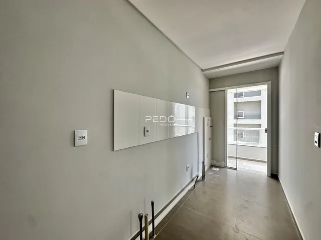 Corredor interno de uma residência com paredes brancas e piso de concreto.