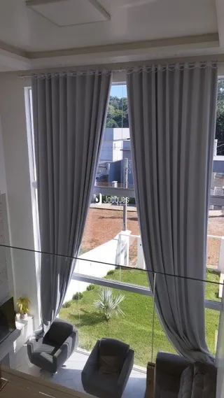 Vista da janela com cortinas claras em uma residência.
