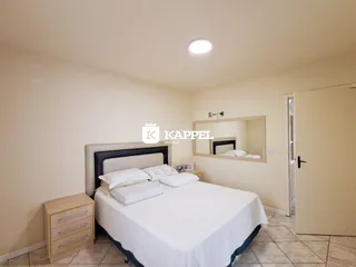Quarto com cama de casal e mesa de cabeceira em um ambiente claro.