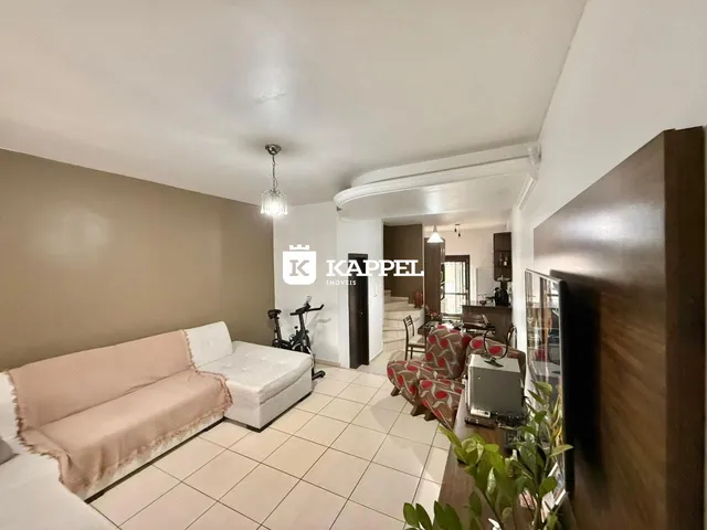 Sala de estar com sofá claro e piso de cerâmica em um imóvel em Lajeado.