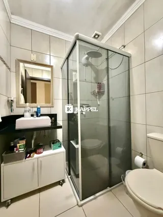 Foto de um banheiro com box de vidro e revestimento branco.